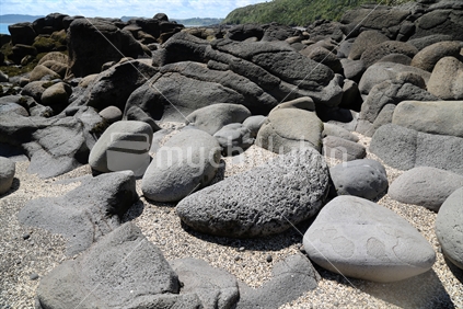 Large rocks on a beach in Raglan.