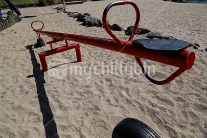 A red seesaw on a playground.