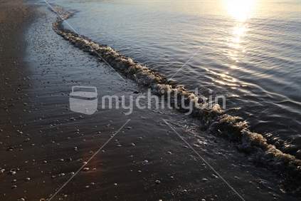 Water edge on Raglan beach at sunset.