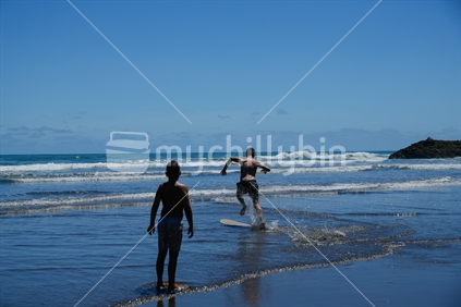 Kids playing in the water at Piha beach in Auckland.