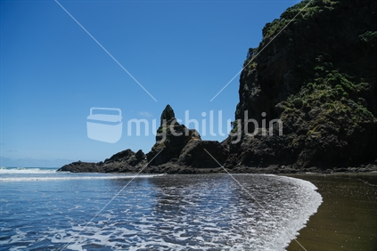 The rock formations on Piha beach in Auckland.  With the sky, sea and sand.
