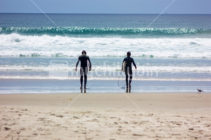 Two people heading out for a surf