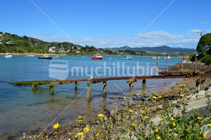 South Island Scene of sailboats, yellow flowers, mountains, rusty pier and blue sky 
